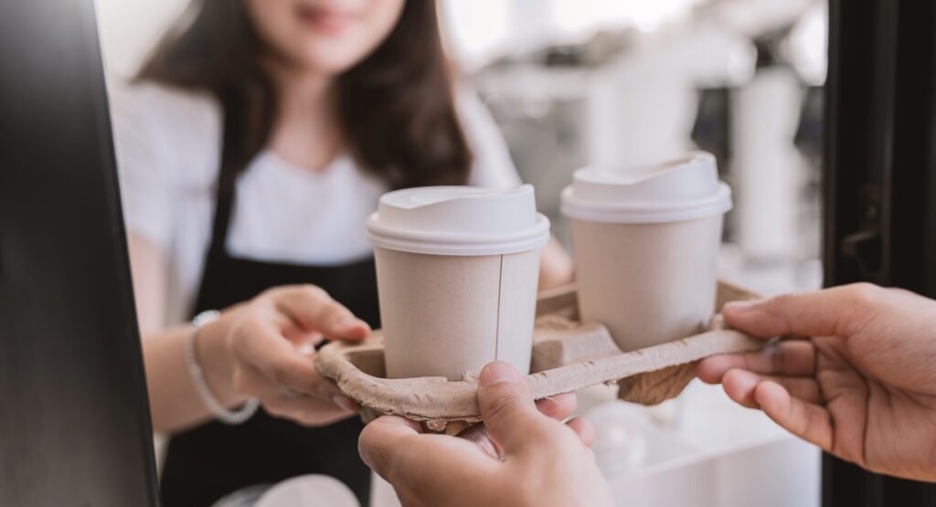 Close up woman hands gives paper coffee cup
